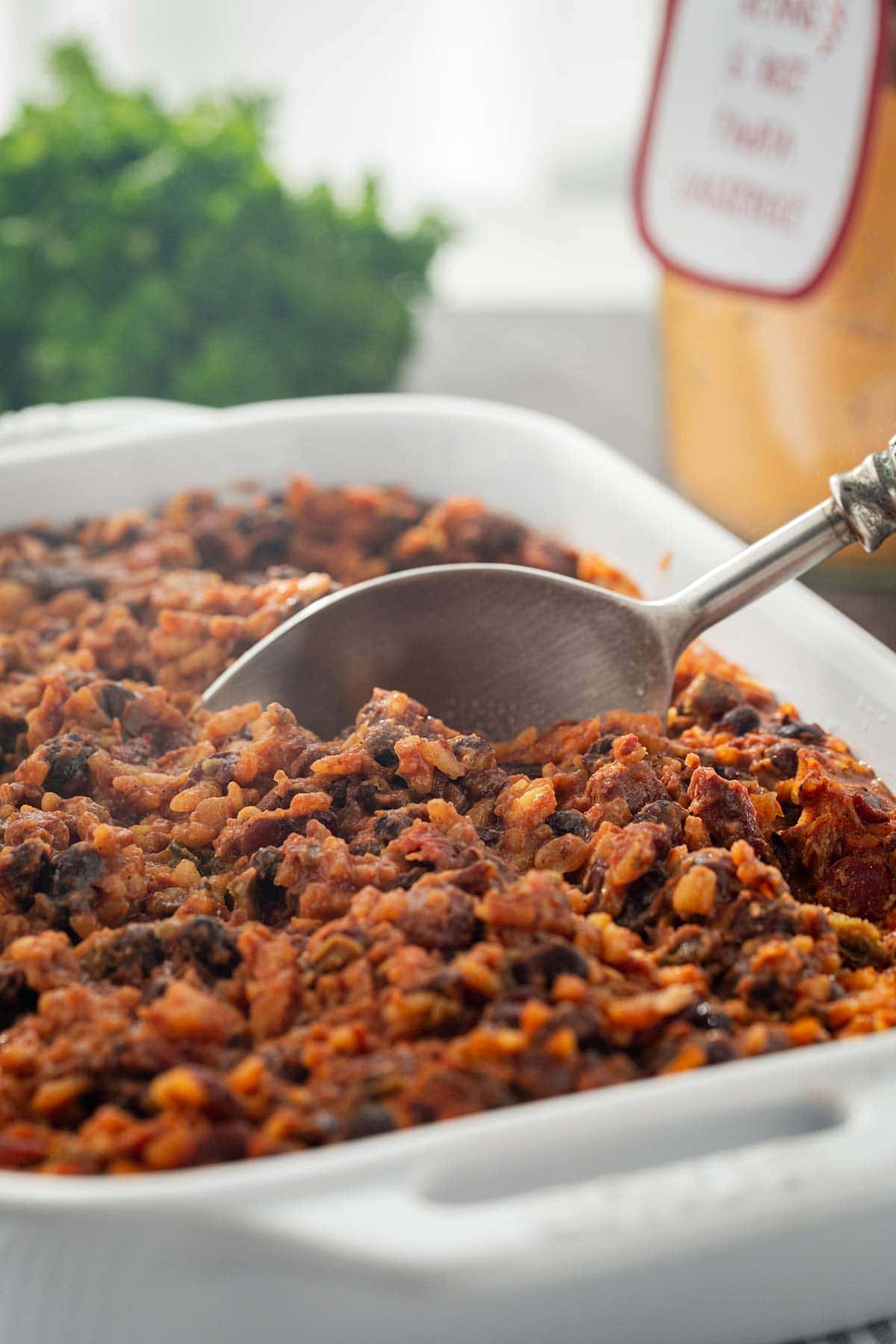 Shot of casserole dish with Bean & Rice Fajita Casserole Meal in a Jar, with spoon scooping out a serving to eat.