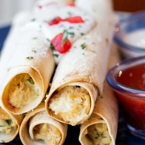Chicken Bacon Ranch Taquitos on a blue plate with dipping sauces.