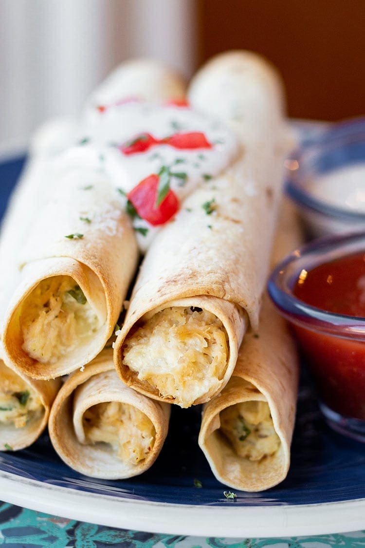 Chicken Bacon Ranch Taquitos on a blue plate with dipping sauces.
