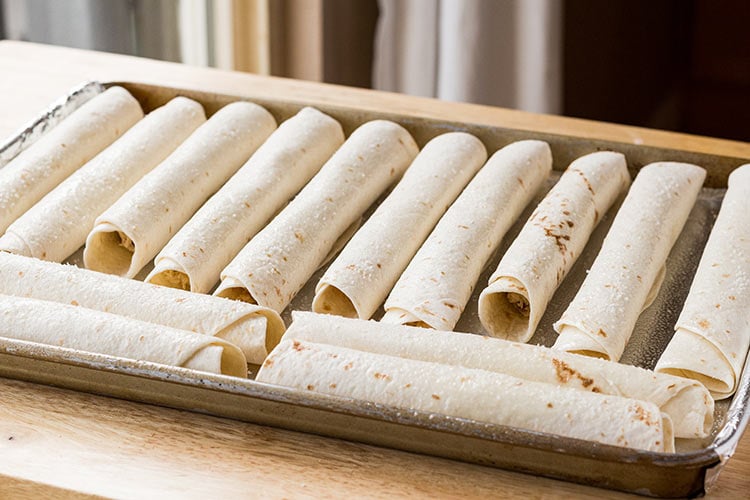 Chicken Bacon Ranch Taquitos placed on a baking sheet ready to be baked.