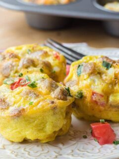 Three sausage egg muffins on a white plate.