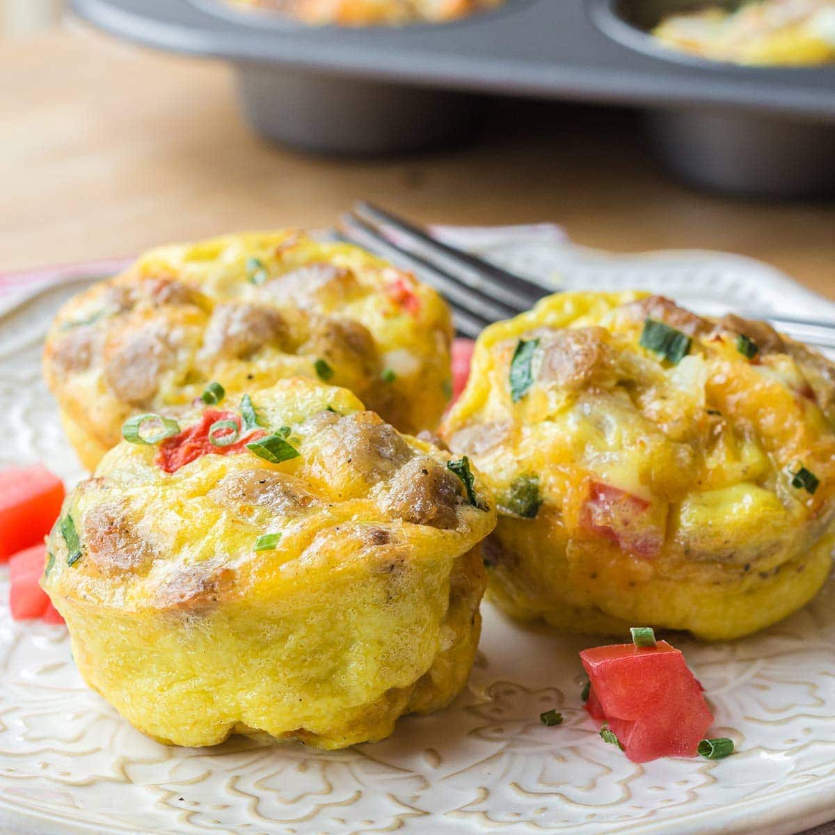 Three sausage egg muffins on a white plate.