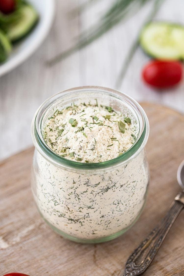 Closeup shot of powdered dry ranch seasoning mix in a small glass jar.