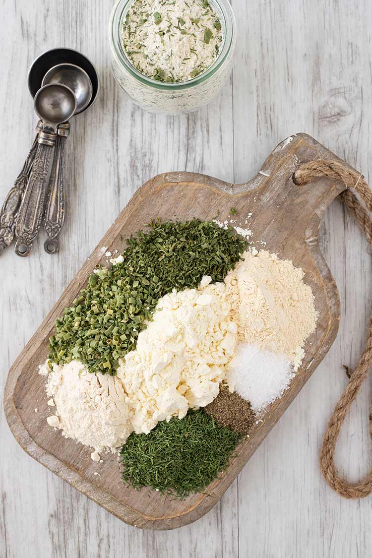 The various powdered ingredients for making Homemade Ranch Dressing Mix laid out on a wooden cutting board.