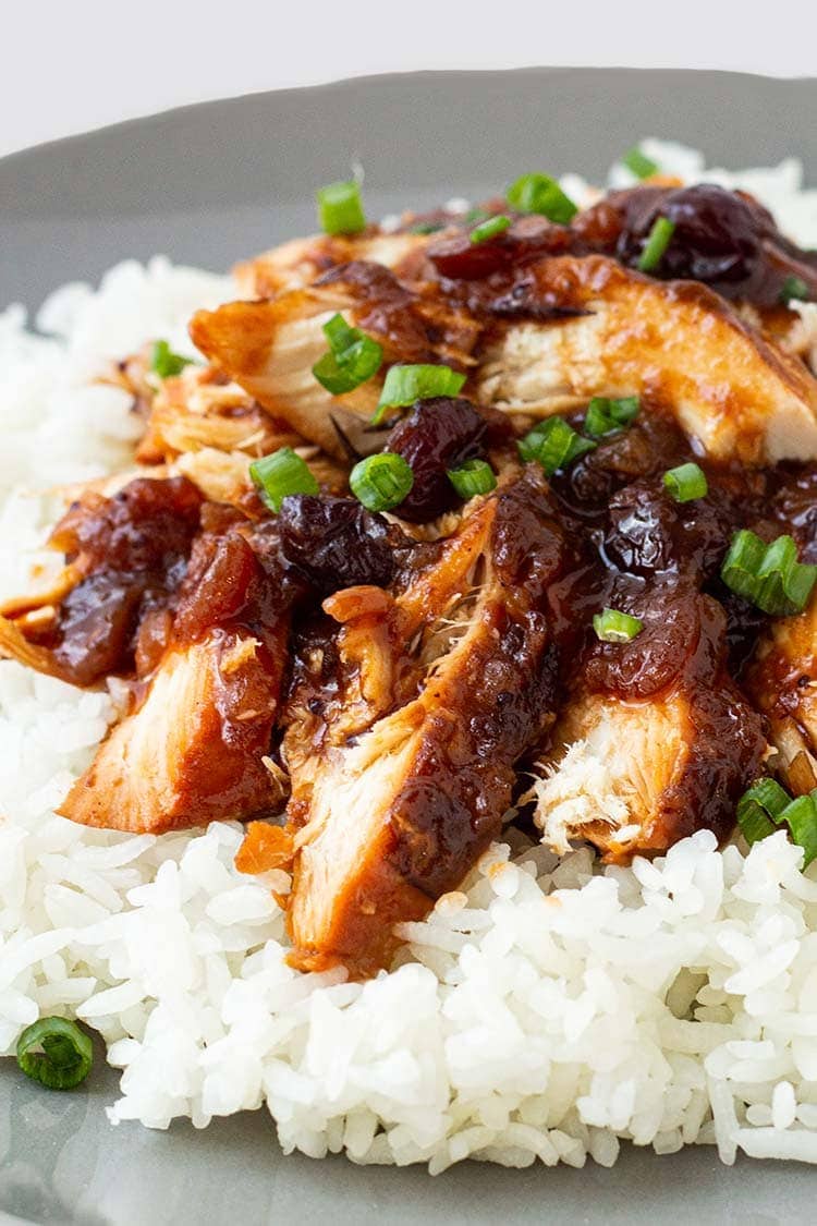 Closeup shot of cranberry catalina chicken on a bed of rice, on a gray plate.