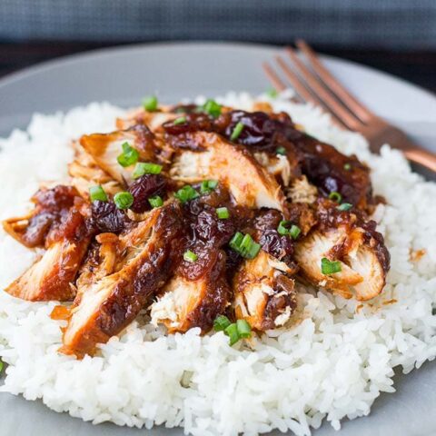 Cranberry Catalina Chicken on a bed of white rice on a gray plate, garnished with sliced green onions.