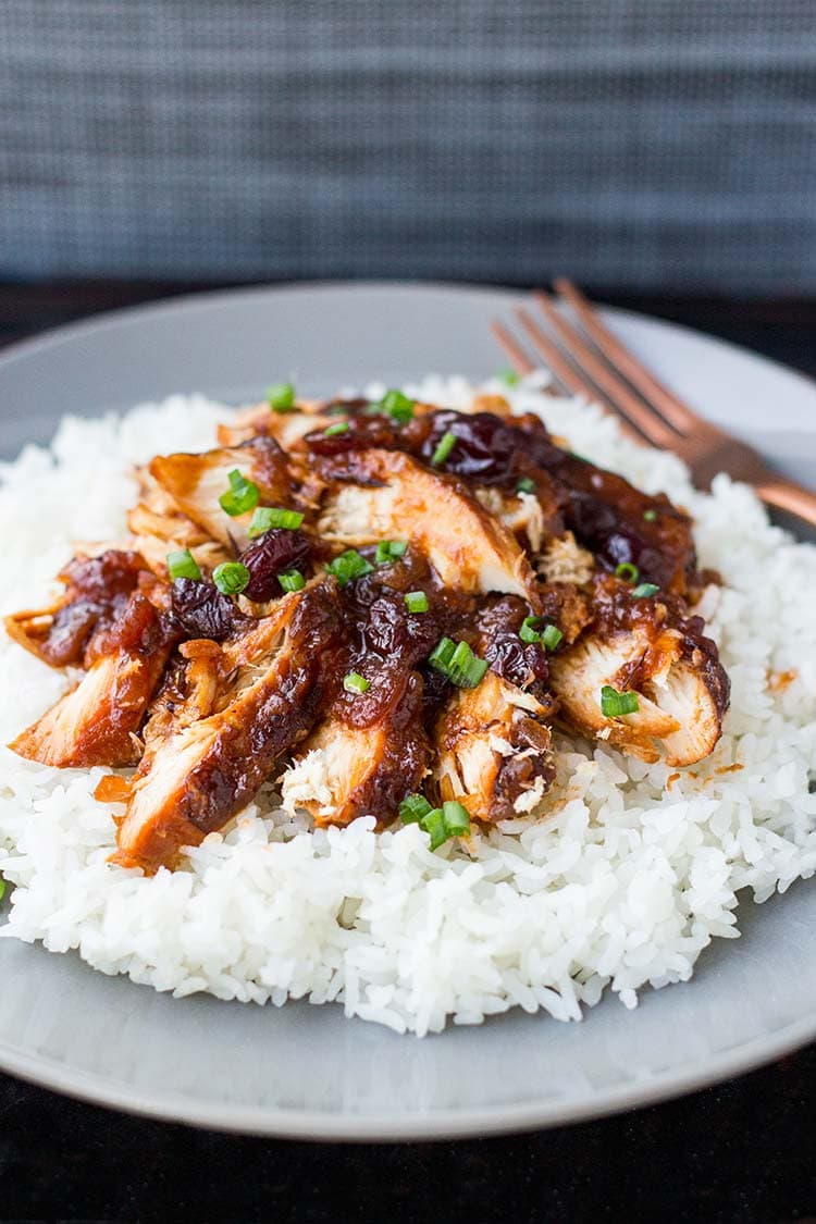 Cranberry Catalina Chicken on a bed of white rice on a gray plate, garnished with sliced green onions.