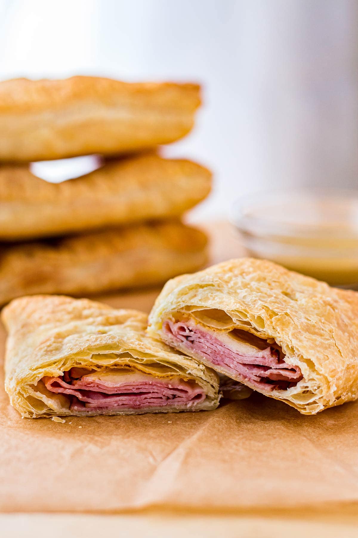 Homemade Ham & Cheese Hot Pockets cut open on cutting board, with stack of hot pockets in background.