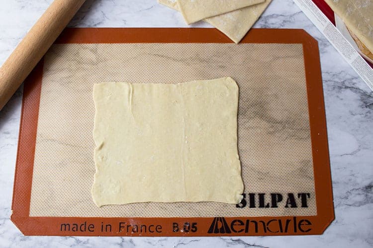 Overhead shot of puff pastry rolled out on silicone mat.