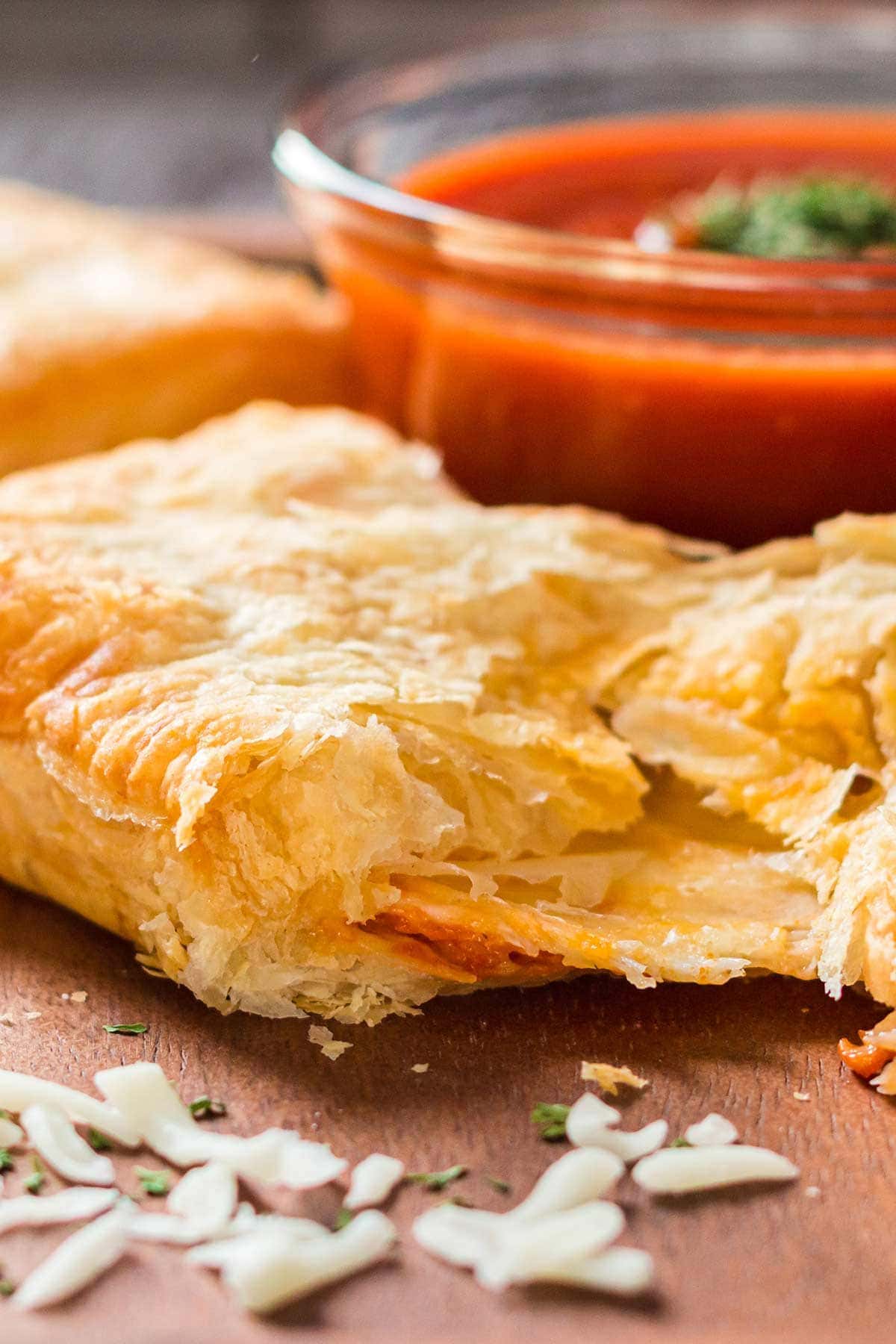 Puff pastry pizza pocket on tray with dipping sauce in background.