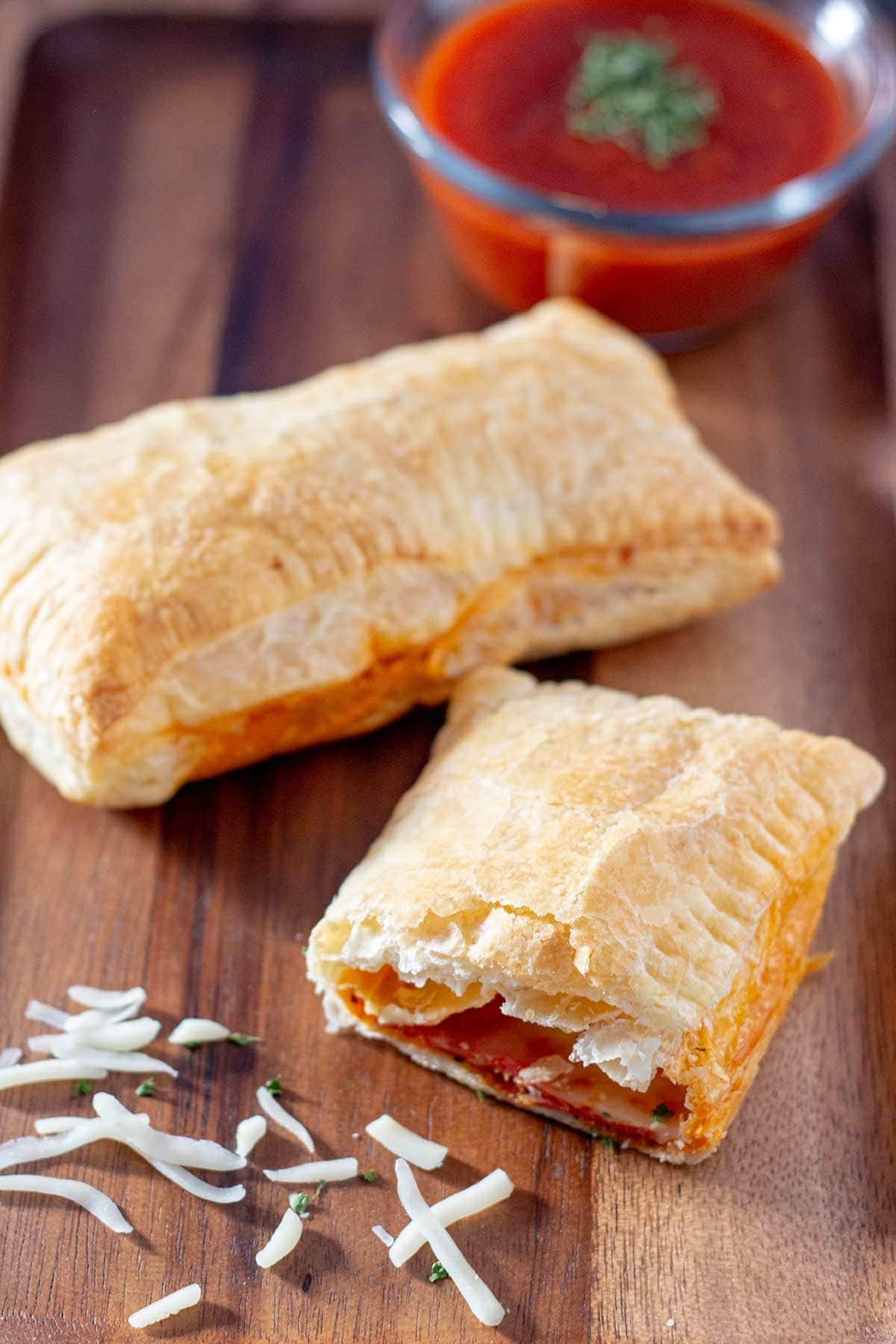 Overhead shot of baked pizza pockets on tray with dipping sauce.