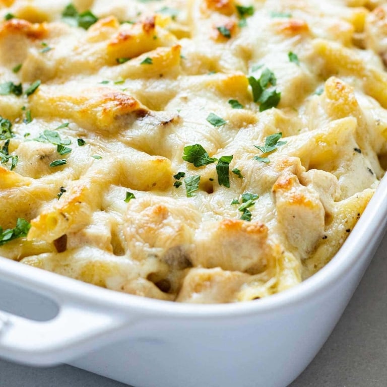 White baking dish with Chicken Alfredo Bake freezer meal, garnished with fresh green parsley.