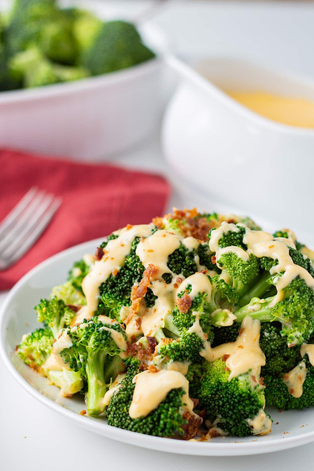 Plate of broccoli drizzled with freezer cheese sauce and garnished with crumbled bacon.