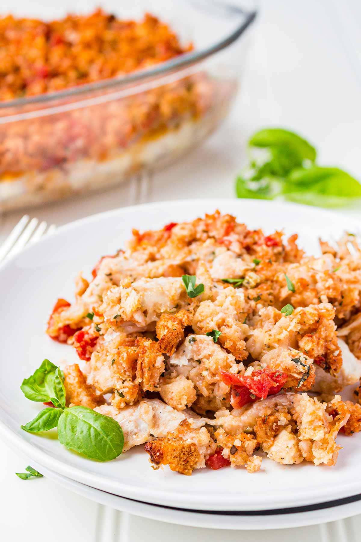 Bruschetta Chicken Bake served on white plate and garnished with fresh basil.