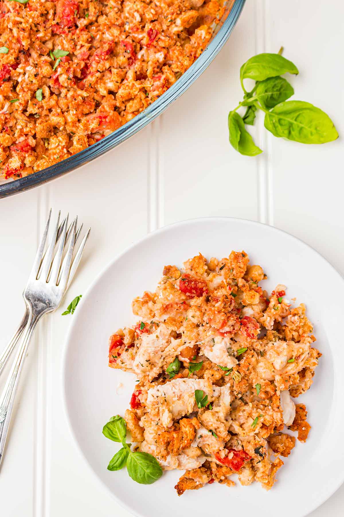 Overhead shot of portion of Bruschetta Chicken Freezer Meal Casserole on a white plate with a white background.