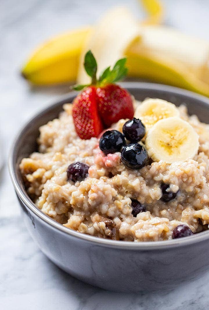 Instant Pot Easy Steel Cut Oats in a gray bowl, topped with fresh strawberries, blueberries and sliced banana.