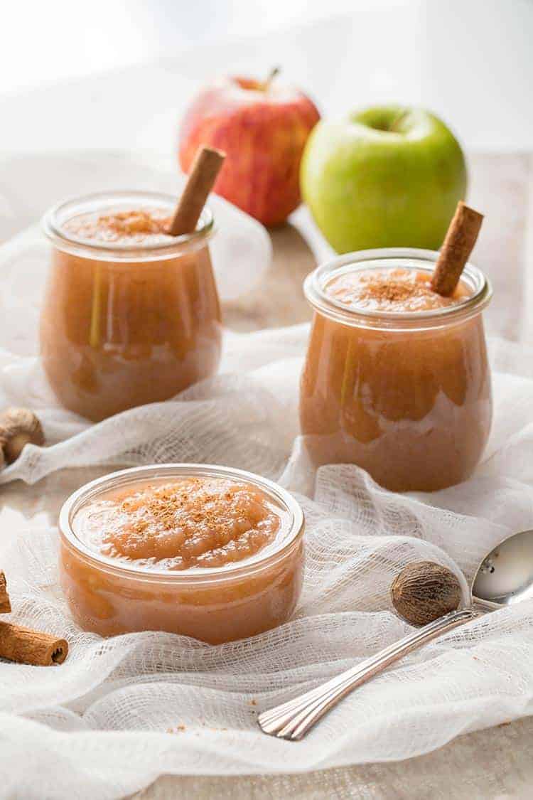 Easy Instant Pot Applesauce in a trio of jars with garnish of nutmeg and cinnamon