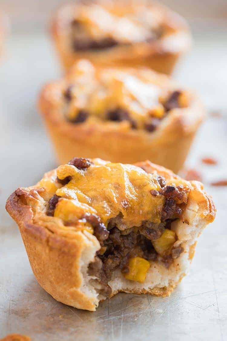 Beefy BBQ Biscuit Cups lined up on tray with meaty filling showing