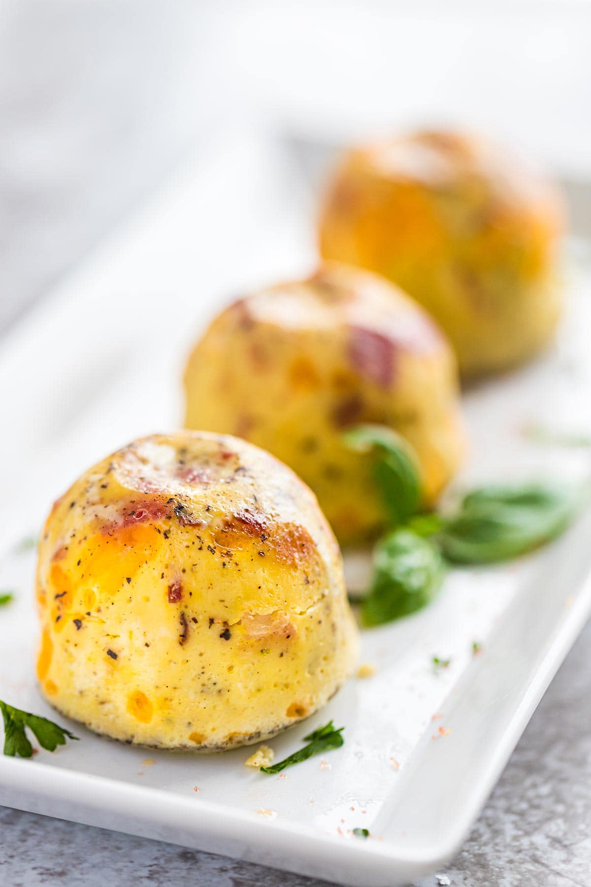 Closeup shot of Instant Pot Keto Egg Bites on plate with fresh basil.