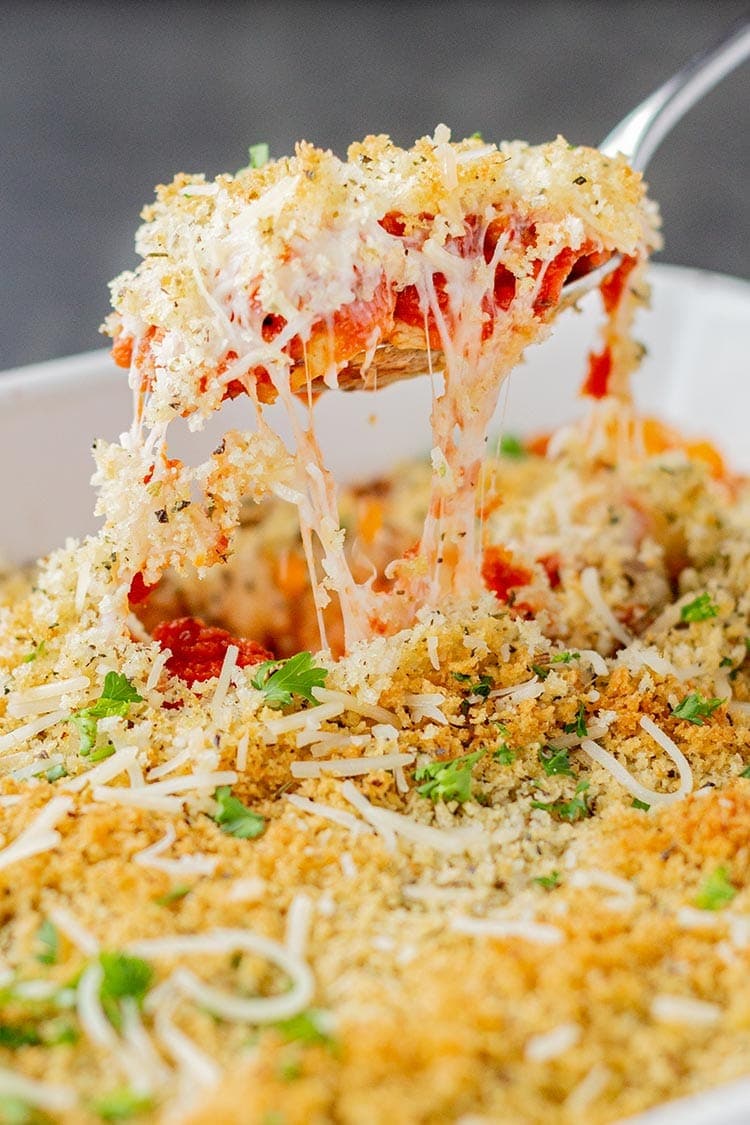 Easy Chicken Parmesan Bake freezer meal being spooned out of baking dish with stretchy mozzarella cheese