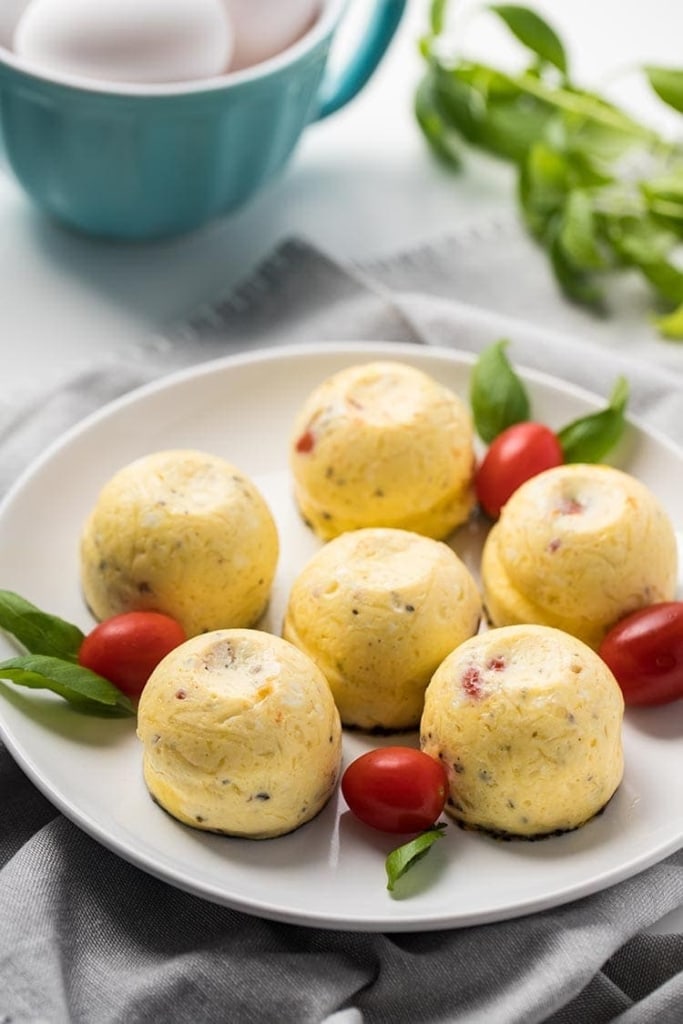 Instant Pot Caprese Egg Bites on a plate with fresh tomatoes and basil