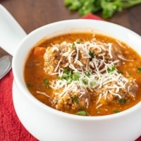 Close up of Instant Pot Meatball Soup in a white soup bowl with shredded cheese