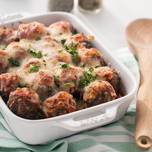 Easy Keto Meatballs in a white baking dish covered with marinara sauce and melted cheese!