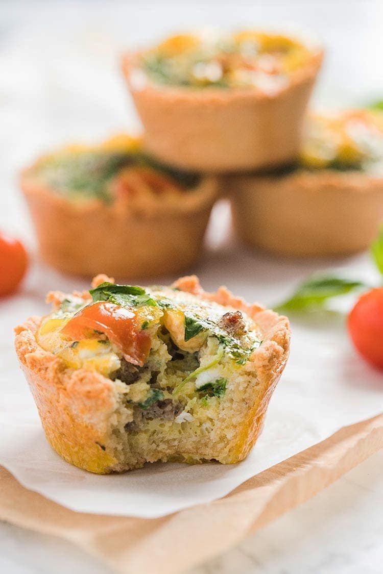 LowCarbMiniQuiches stacked on the counter with one in front showing the inside of the mini quiche and its ingredients