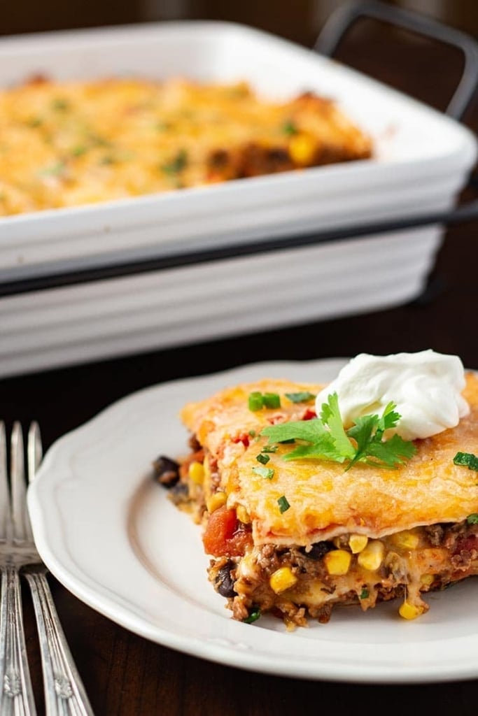 Make-Ahead Mexican Lasagna dished onto a white plate and garnished with sour cream and fresh cilantro