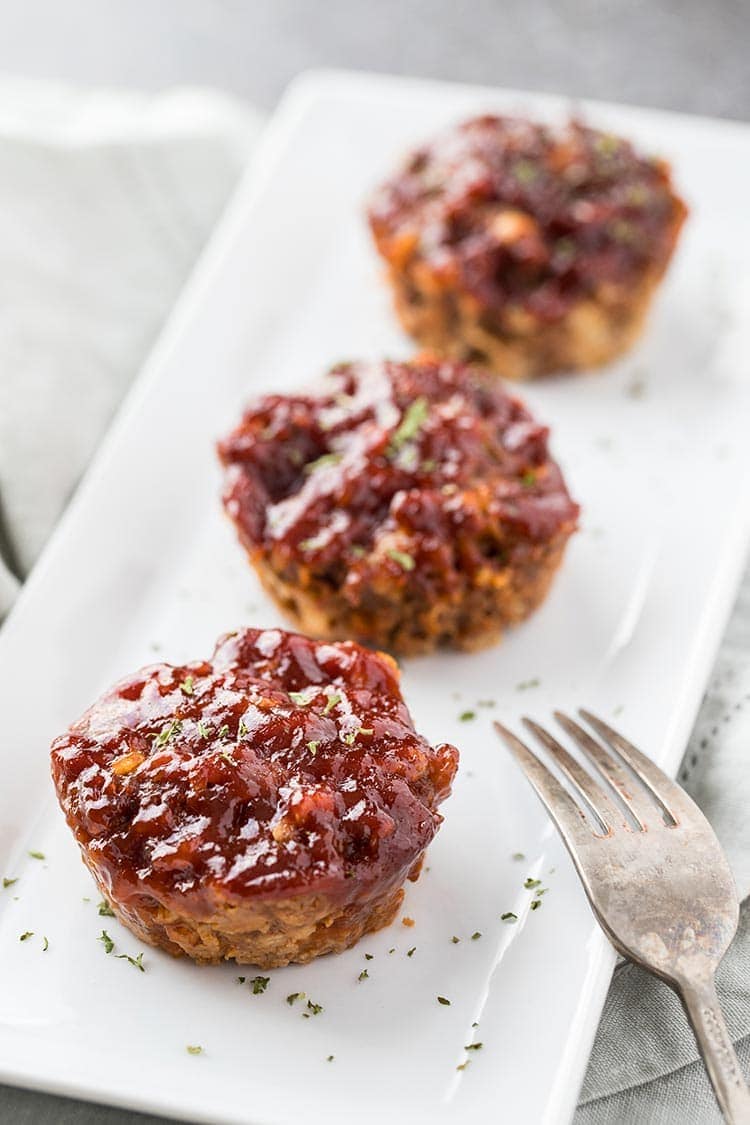 Mini Mozzarella Meatloaf Muffins lined up on a white plate and garnished with parsley
