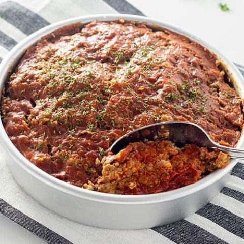 Instant Pot Meatloaf in a round cake pan on a blue striped towel.