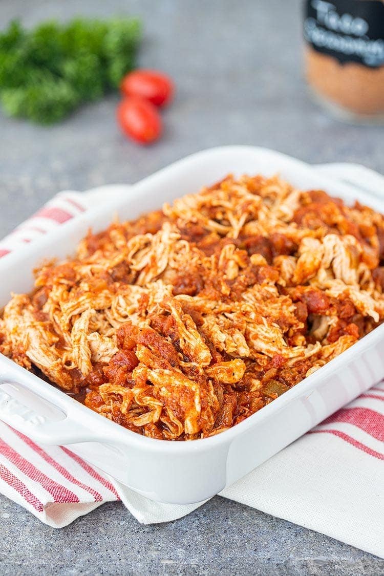 Instant Pot Salsa Chicken in a white baking dish on gray countertop.