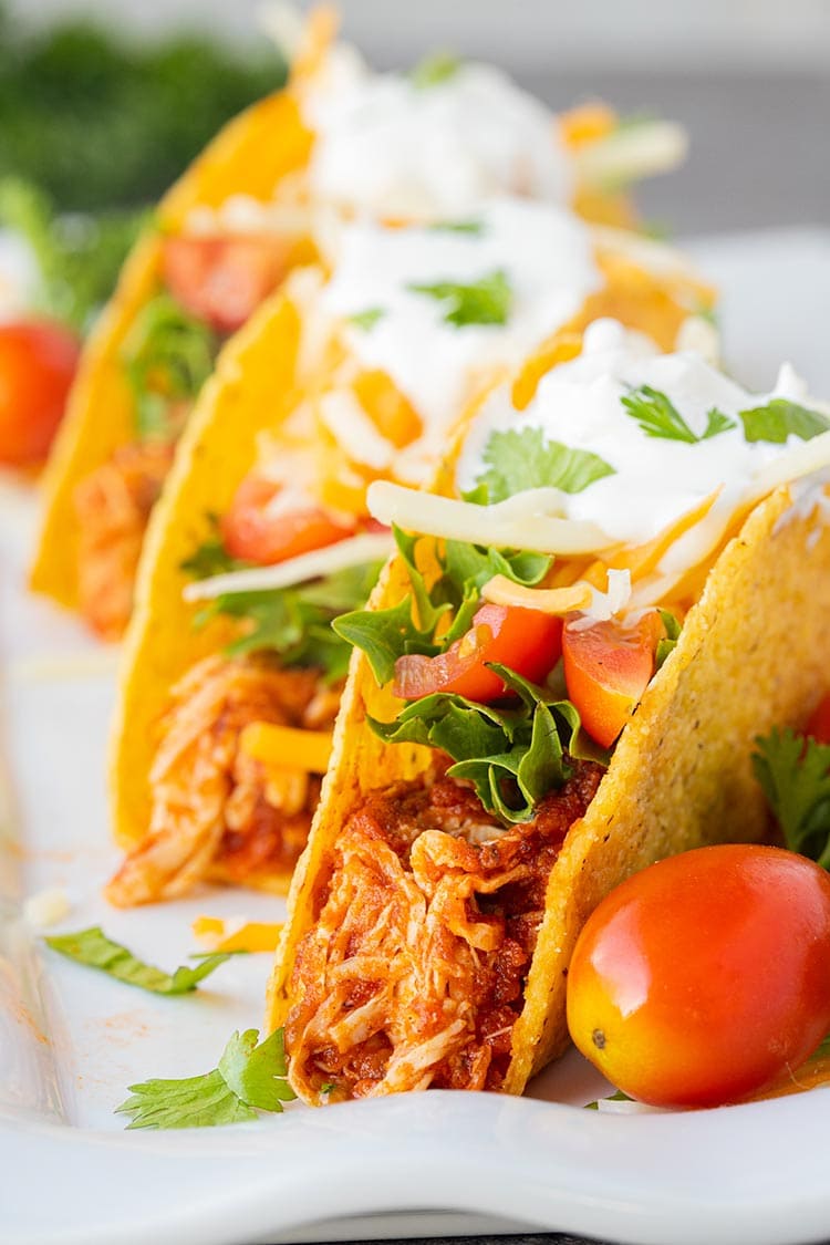 Instant Pot Salsa Chicken used in tacos, sitting on white platter.