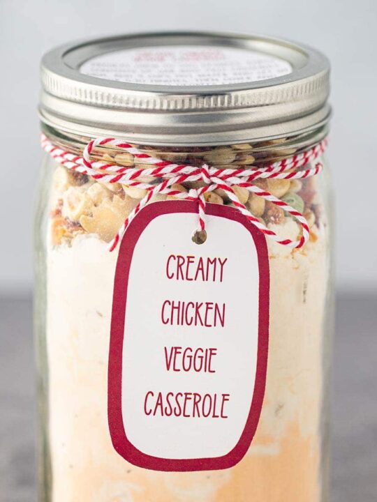 Mason jar filled with dry ingredients used in Creamy Chicken Veggie Casserole, with printed label tied on to outside of jar.