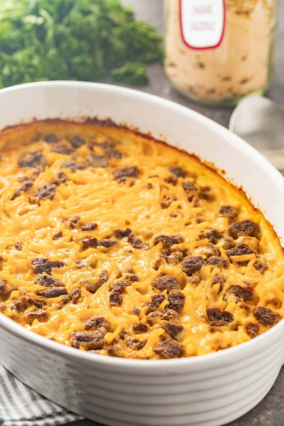 White oval dish showing baked Potato Cheese Sausage Casserole for an easy meal.