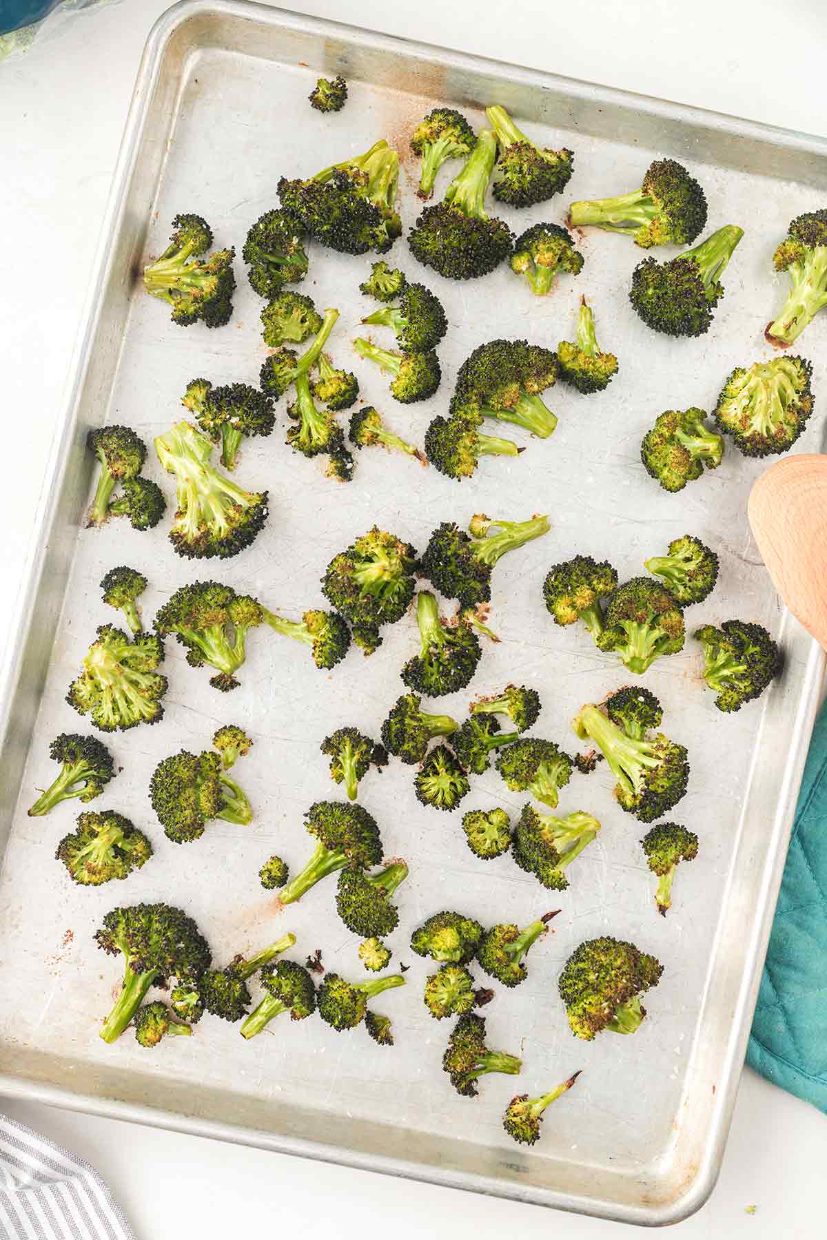 Overhead shot of roasted broccoli on a silver baking sheet just out of the oven.