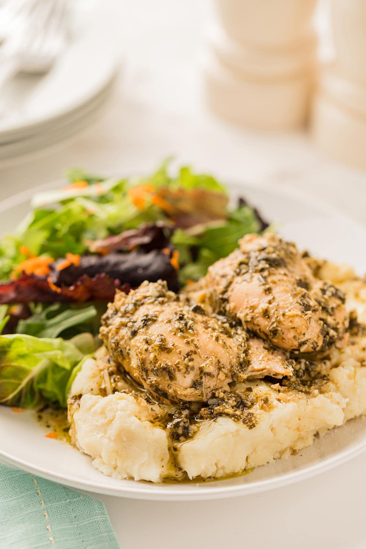 Slow Cooker Pesto Ranch Chicken served on to of mashed potatoes with a simple green salad.
