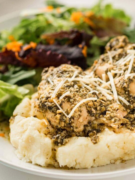 Pesto Ranch Chicken on a bed of mashed potatoes, garnished with shredded Parmesan cheese.