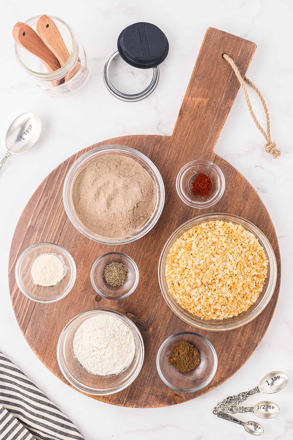 Overhead shot of round cutting board underneath glass bowls of dry ingredients for making onion soup mix.