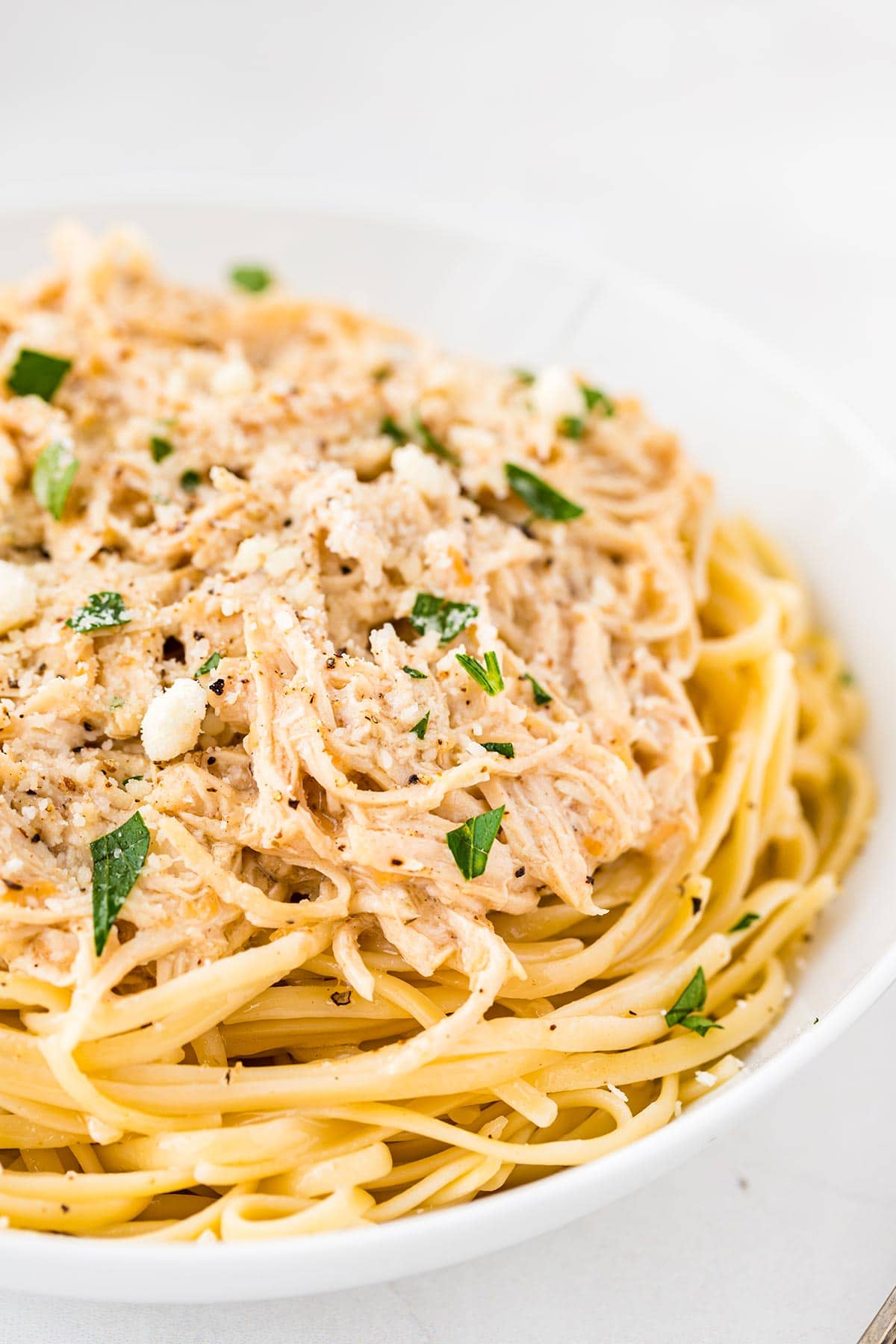 Close up shot of caesar chicken served in a bowl over pasta noodles.