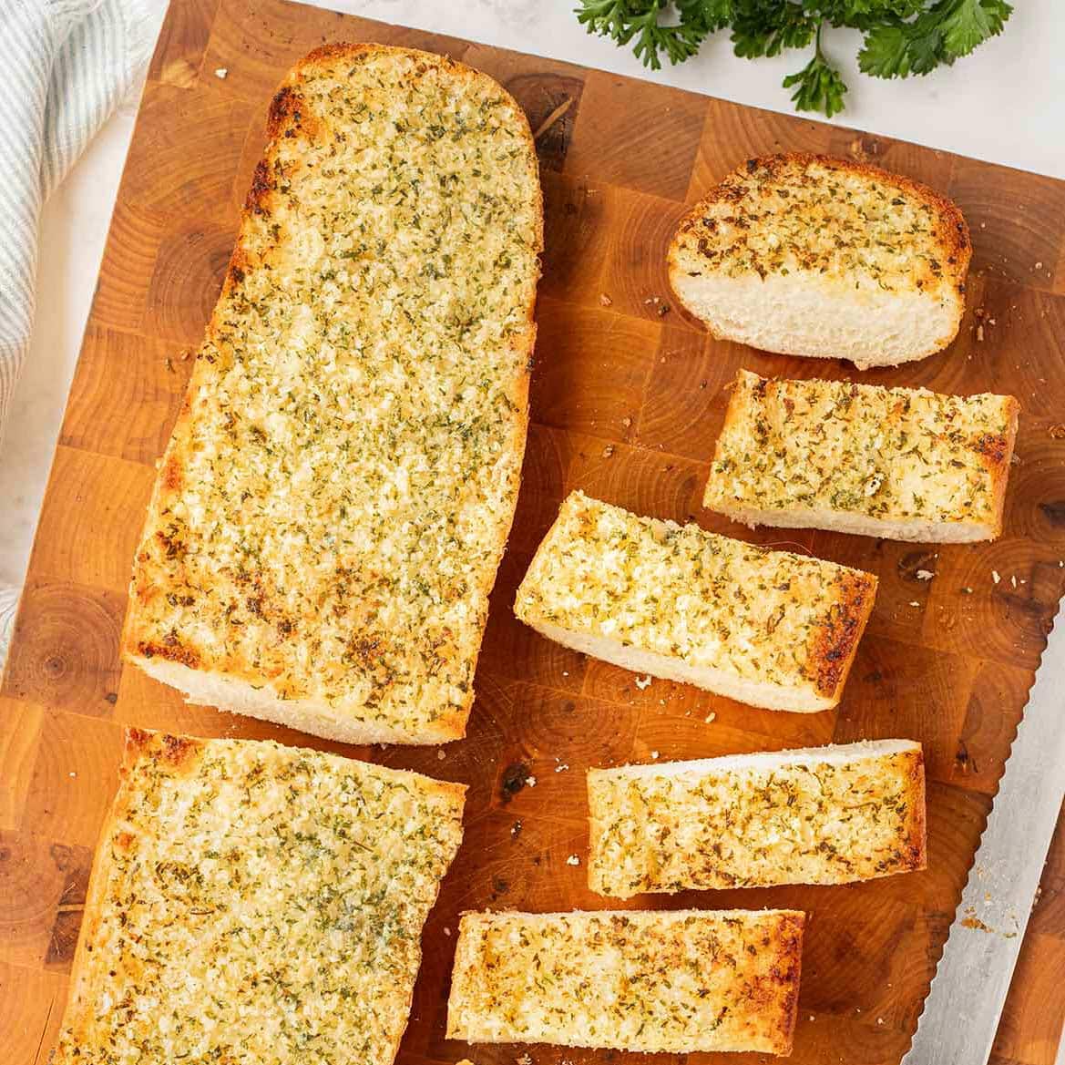 Baked make-ahead freezer garlic bread on a wooden cutting board.