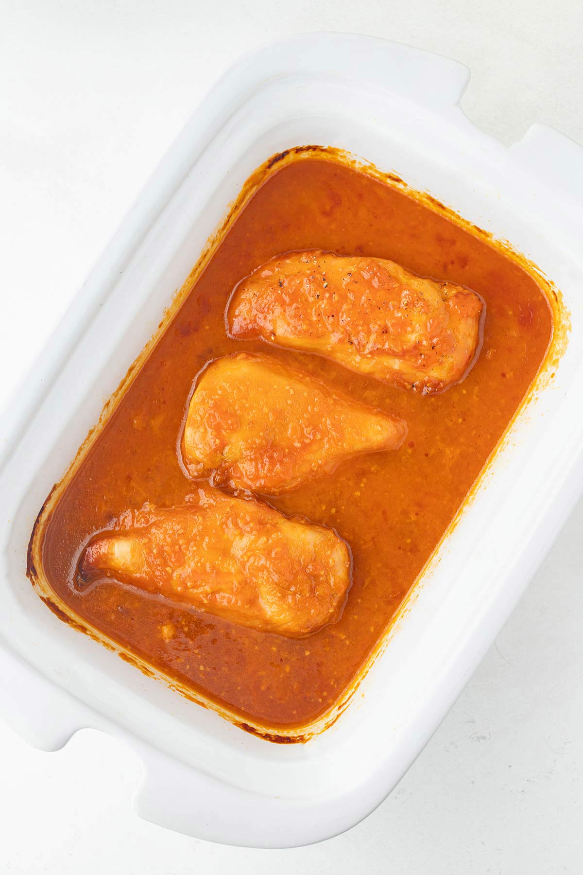 Overhead shot of Apricot Preserves Chicken Recipe cooking in a slow cooker.