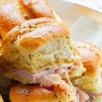 Close up of a ham and cheese hawaiian sweet roll slider.