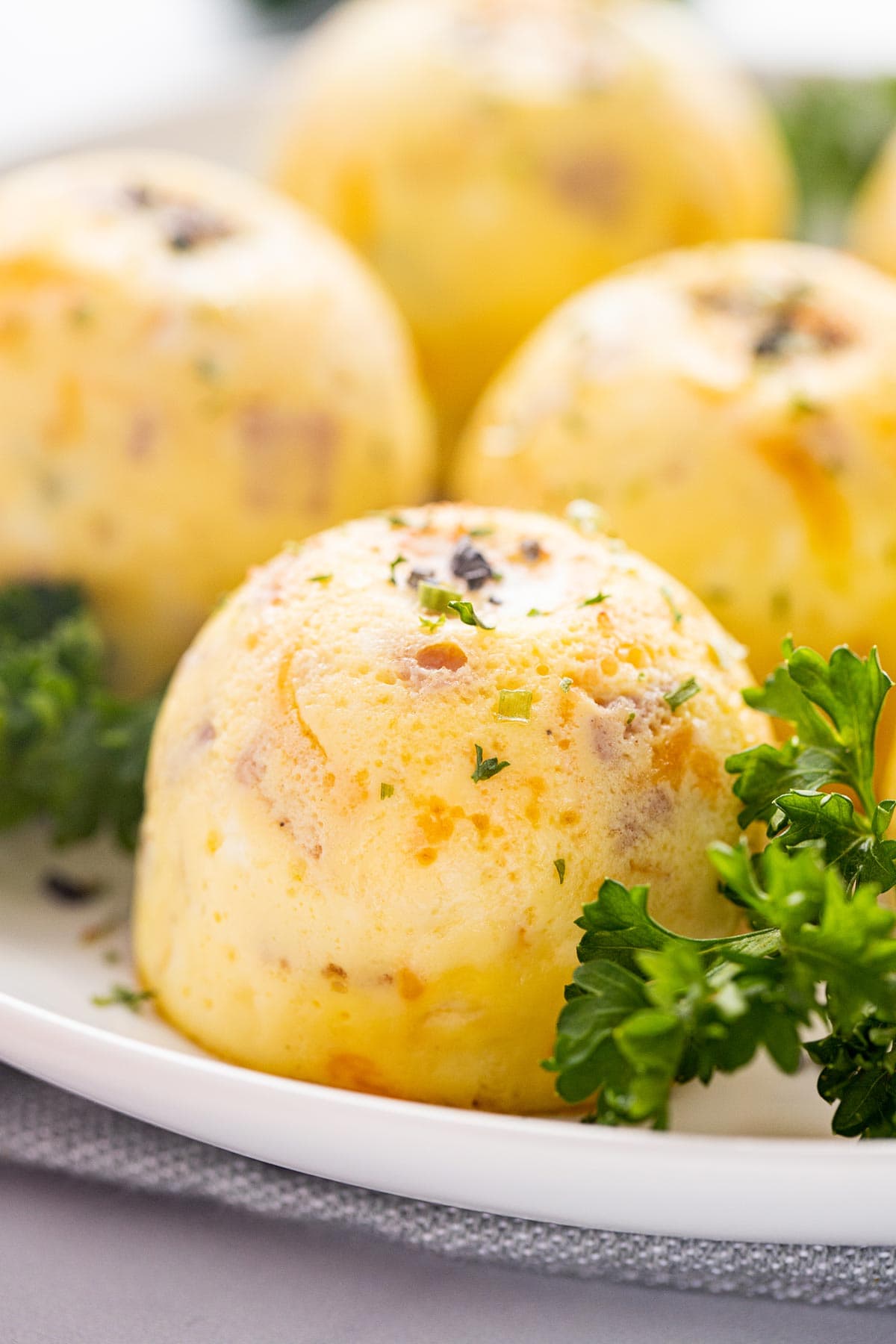 Closeup shot of cooked Instant Pot Denver Omelet Egg Bite on plate with fresh parsley.